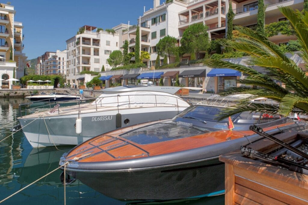 Luxury yachts in the marina alongside modern residential buildings in Montenegro, ideal for selling and renting luxury properties on the coast.