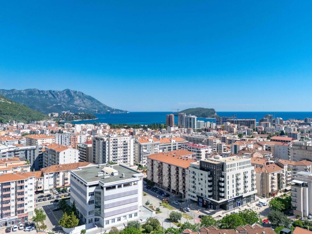 View of the city Montenegro with the sea and mountains in the background, modern residential and commercial buildings, sunny weather.
