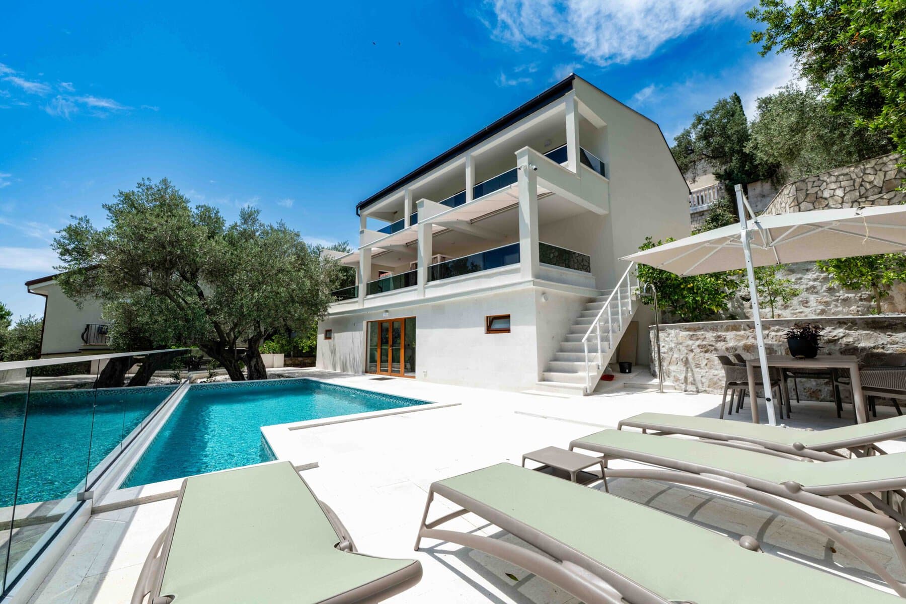 Luxury modern villa with a pool and terraces in Montenegro, surrounded by greenery and beautiful sea views.